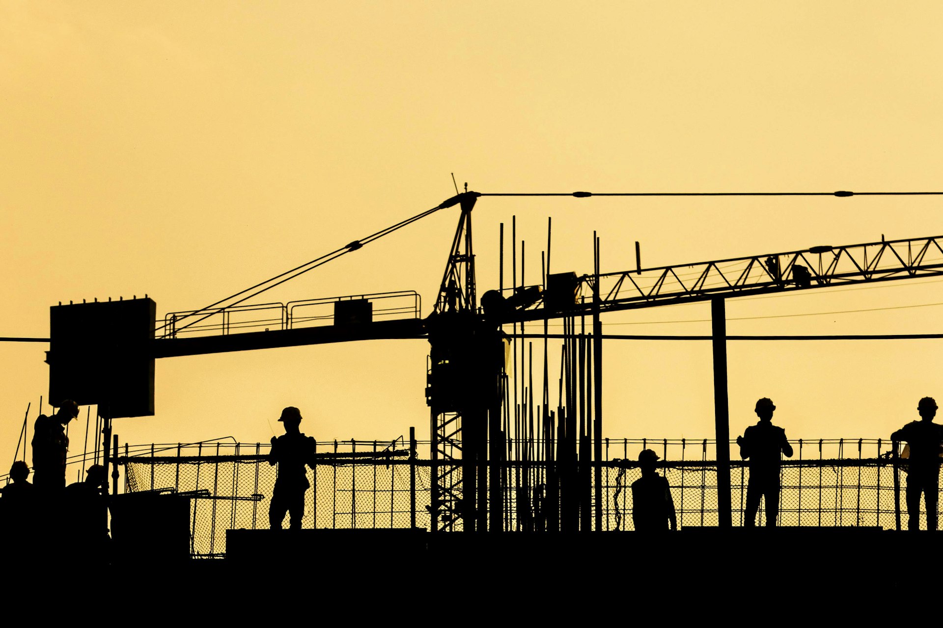 Workers on a building site silhouetted against the sunset