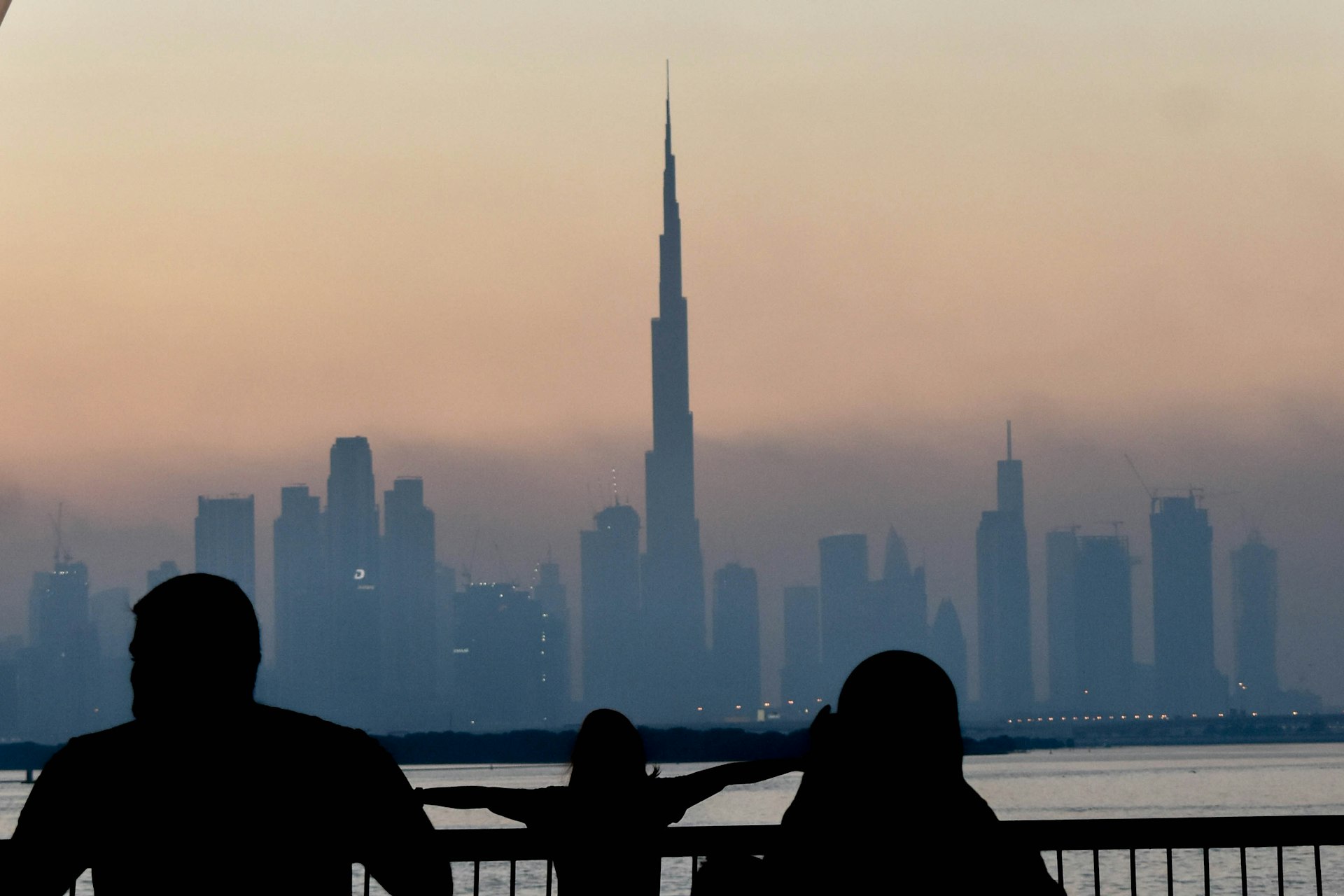 A family watching the sun set over a Gulf city skyline together